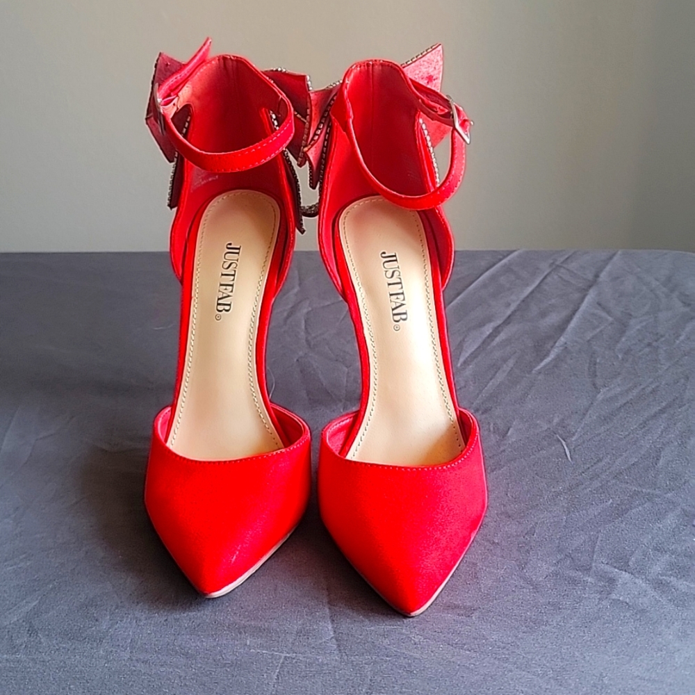 Red ankle strap stiletto heels with rhinestone bow in the back.